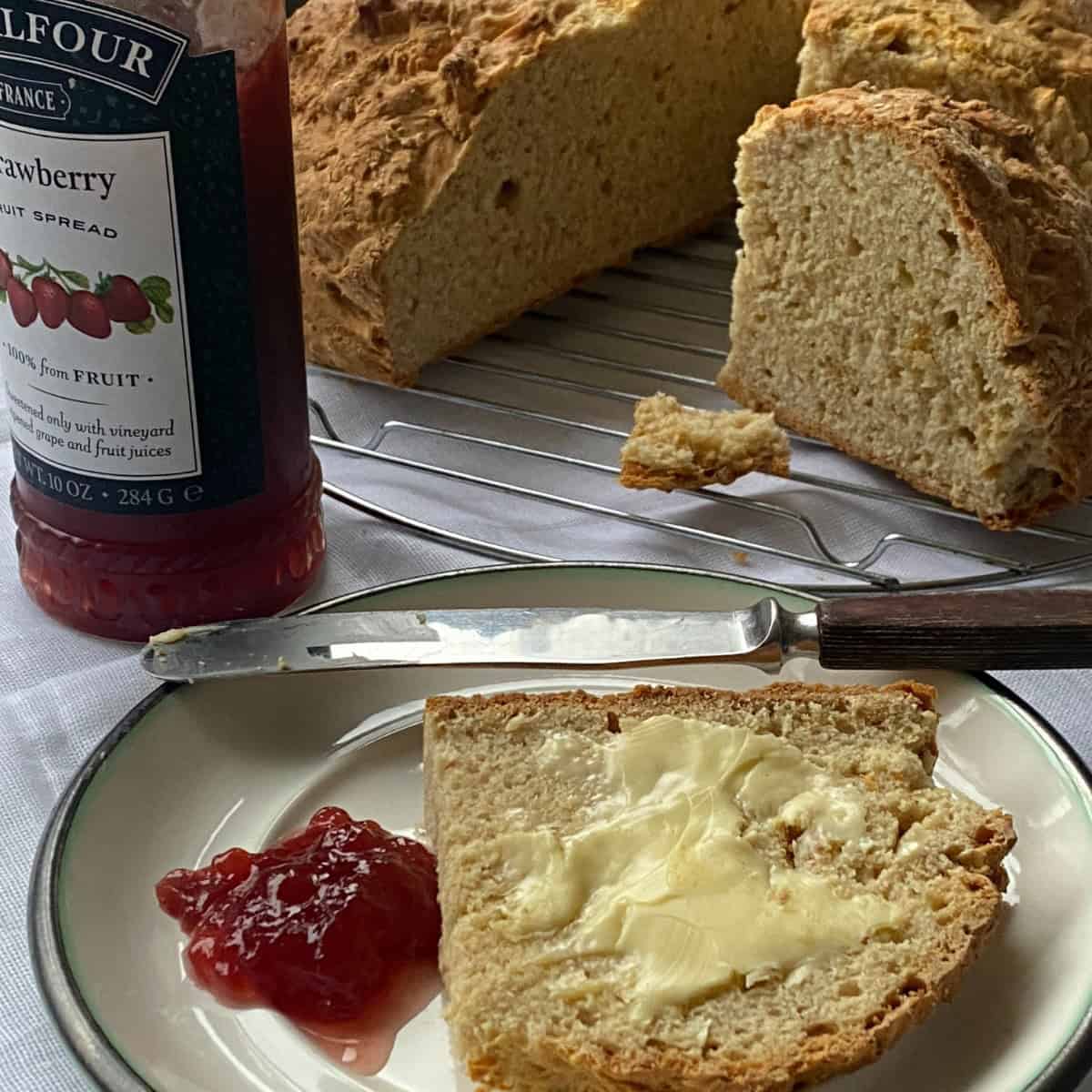 Fresh baked Soda Bread with butter and strawberry jam on a plate.