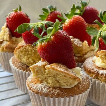 Fresh strawberry cupcakes topped with whole strawberries and powdered sugar. Perfect for desserts and baking inspiration.