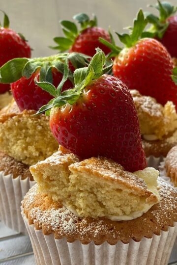 Fresh strawberry cupcakes topped with whole strawberries and powdered sugar. Perfect for desserts and baking inspiration.