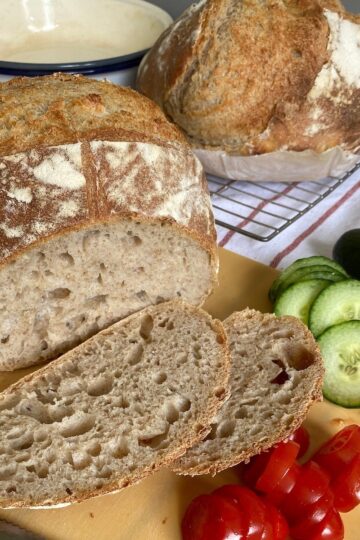 Sliced sourdough with tomato and cucumber on the side.