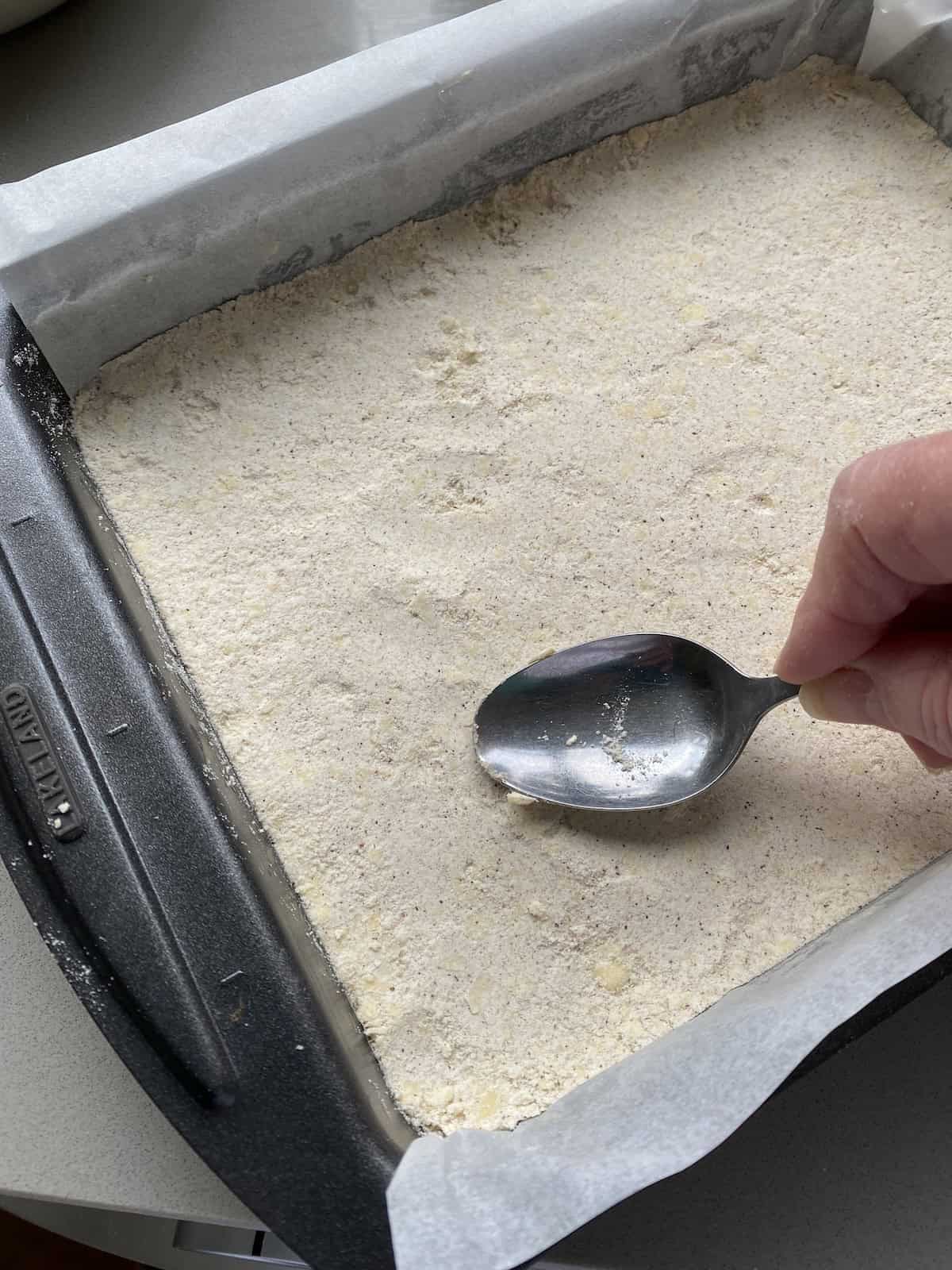 Flattening the Crumble base with the back of a spoon.