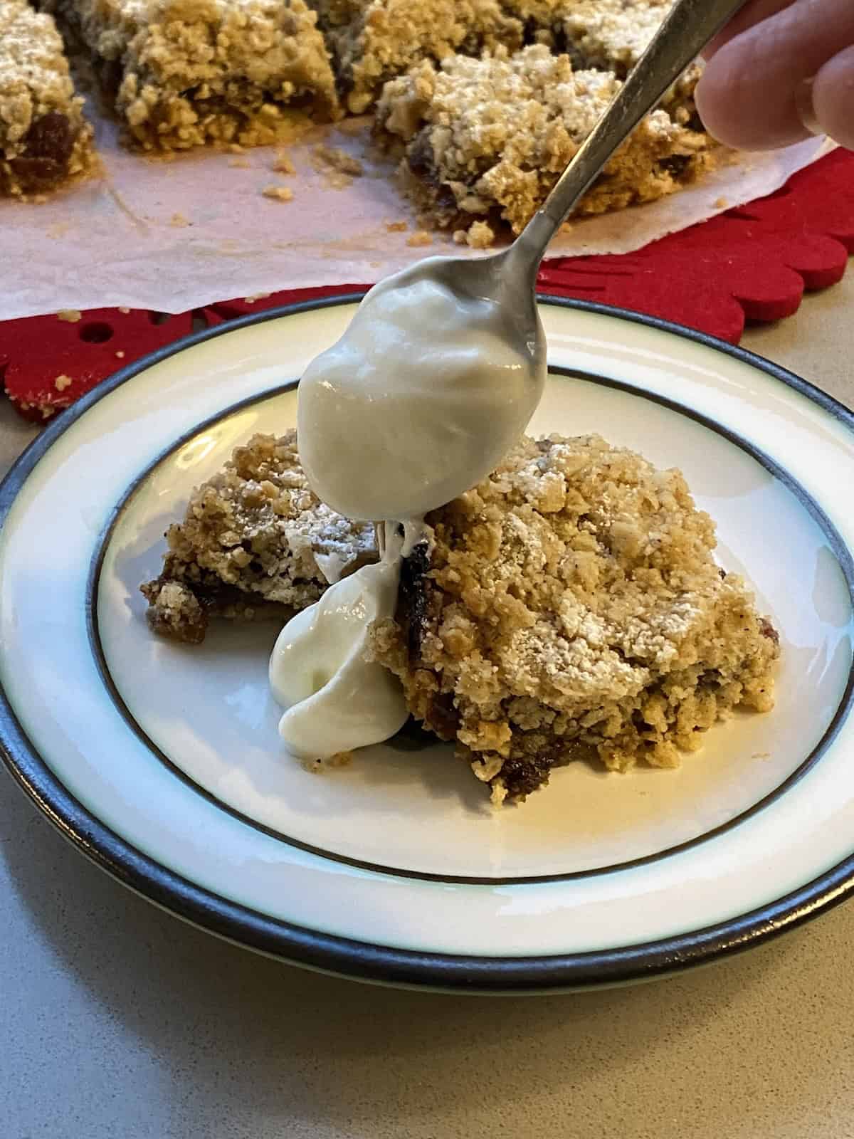 Slices of Mincemeat Crumble Traybake served with plain yogurt.