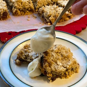 Mincemeat Crumble Traybake with a spoon pouring yogurt on the top.