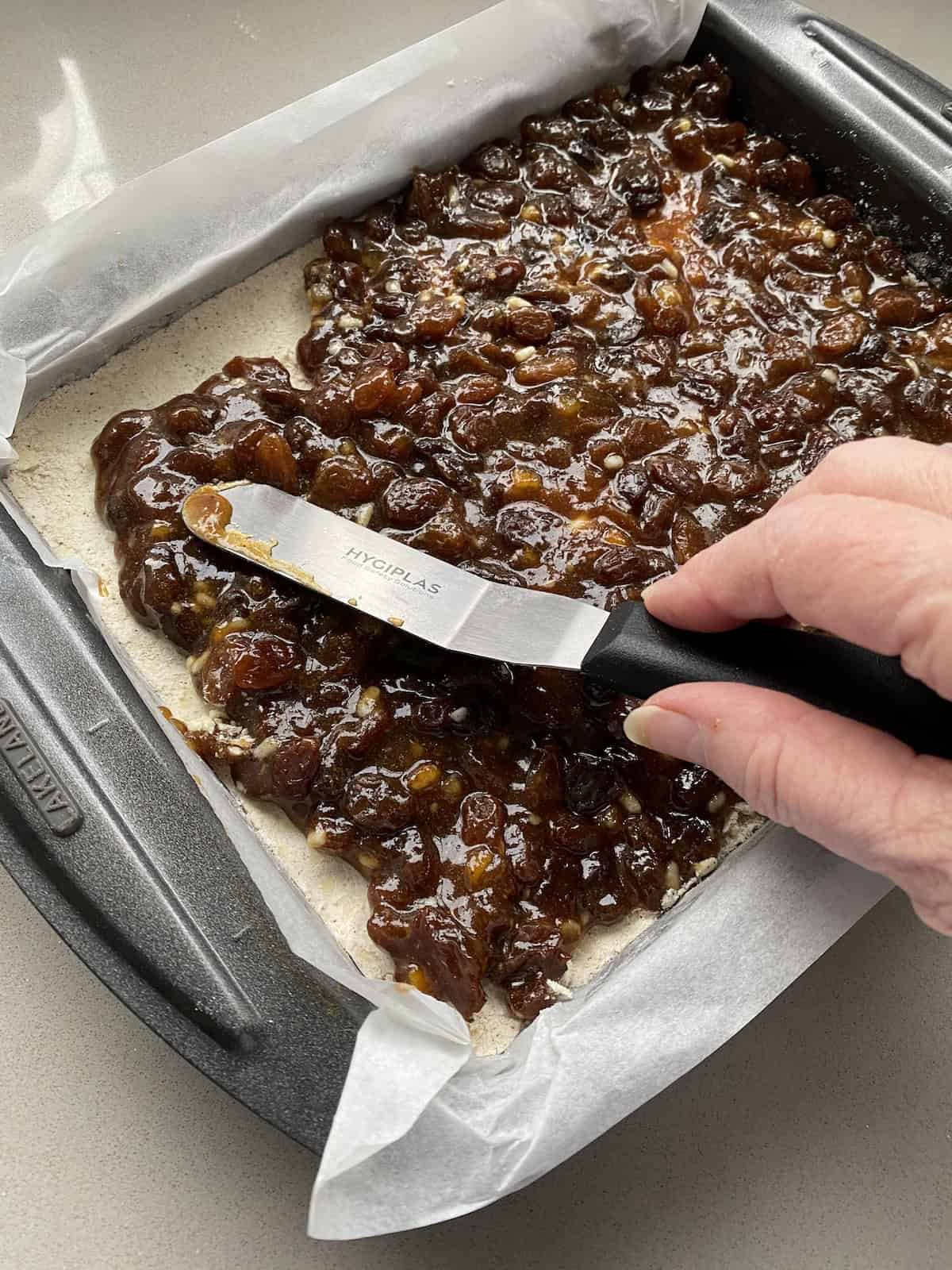 Sweet Mincemeat being spread over a crumble base.