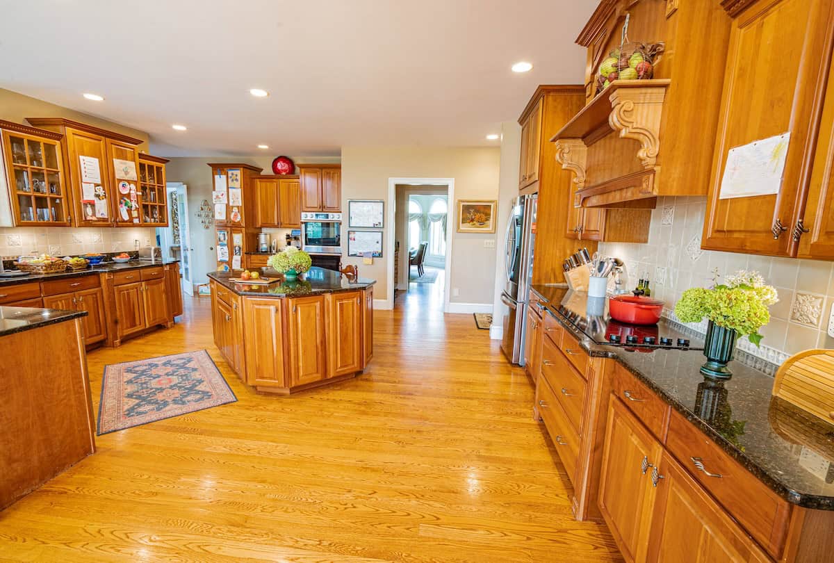 Jessie-Sierra's large kitchen surrounded by wooden units and shelving with an island in the middle.