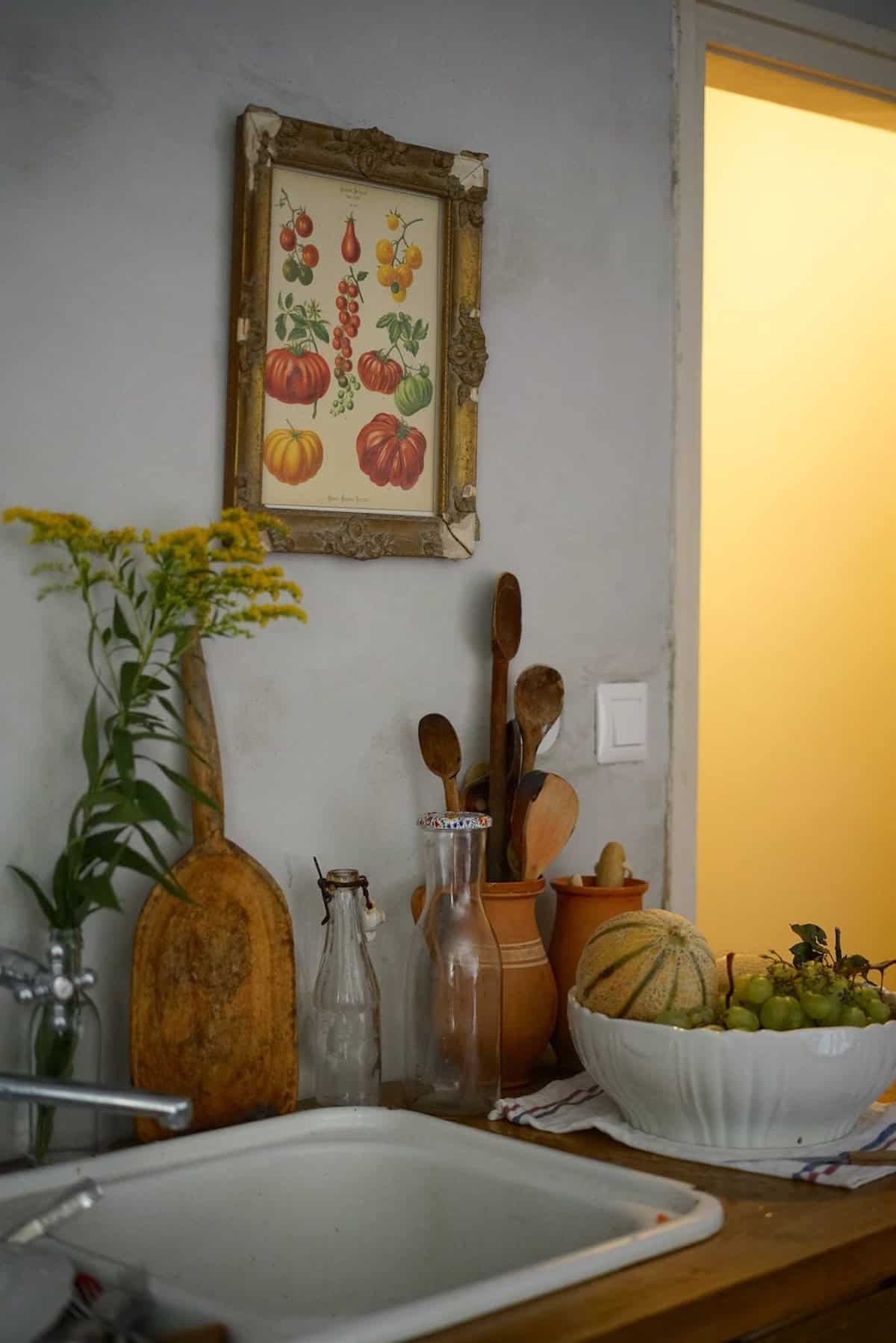 White sink with bottles and dishes of fruit on the counter at the side.