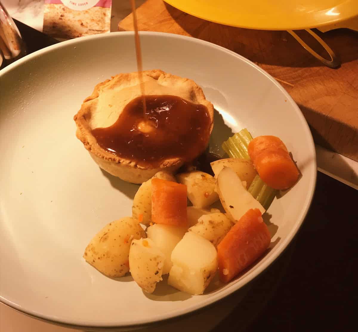 Veganised Scotch Pie served with vegetables on a light coloured plate.