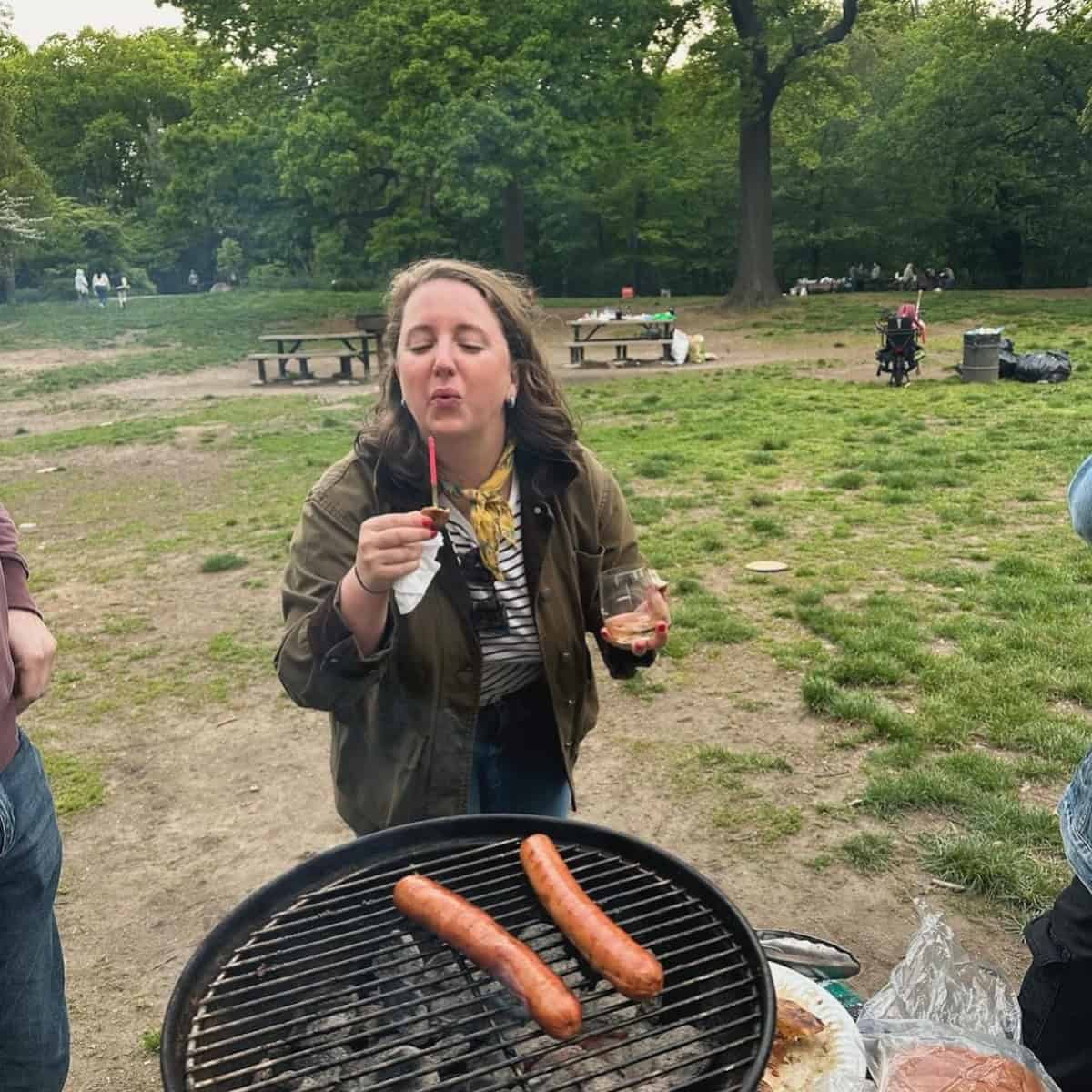 Brianna by a BBQ of sausages. Brianna at a BBQ.