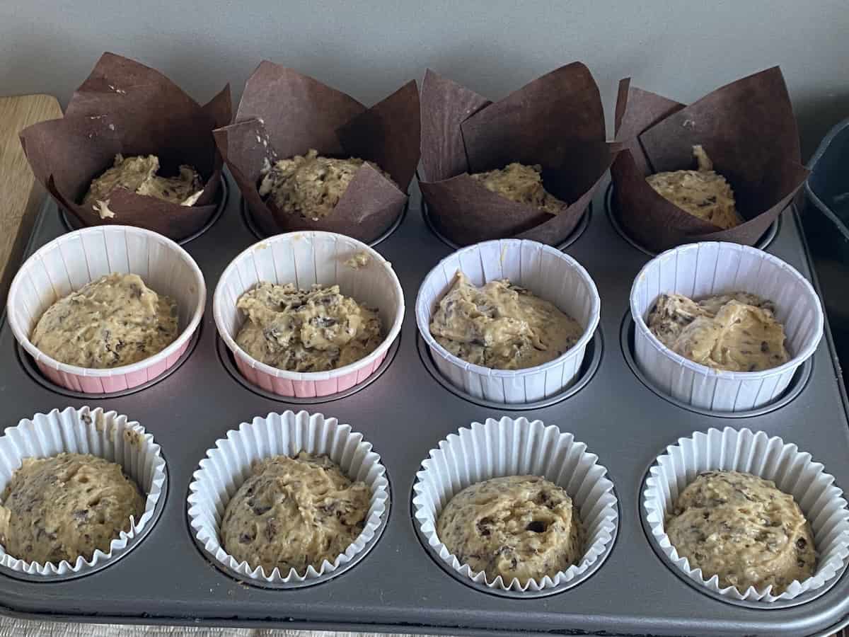 Paper cases filled with Muffin batter placed in a 12 holed muffin tin.