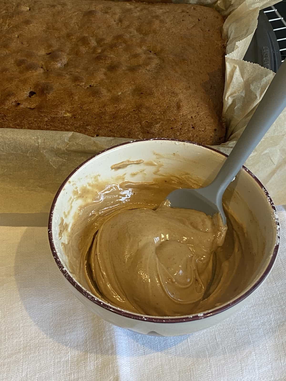 Coffee Cake with Coffee Frosting and Crushed Walnuts. Coffee glaze in a small mixing bowl.