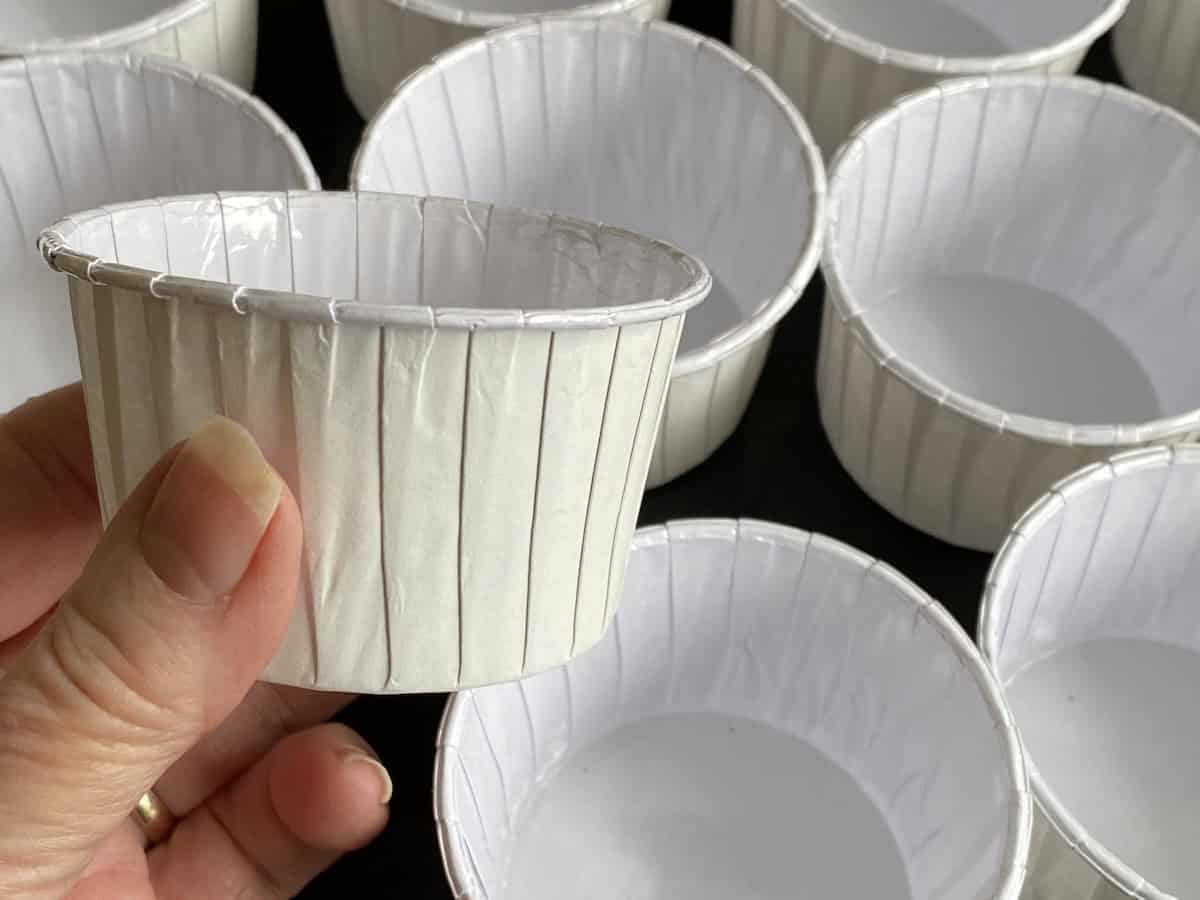 Large Baking Muffins cups on a tray, with a hand holding one of them.