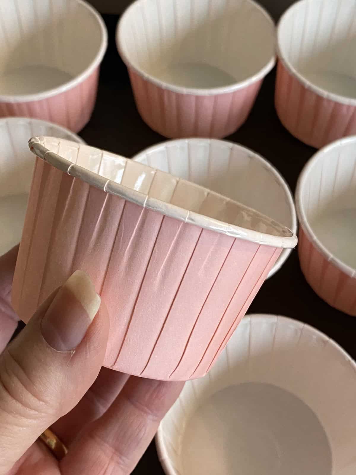 Placing 12 large pink muffin cups on a baking tray for wholesome apple and oat breakfast muffins.