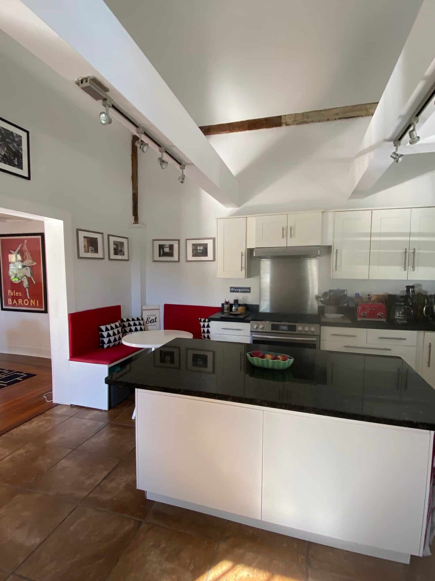 Large bright kitchen with dark counter top and island in the middle.