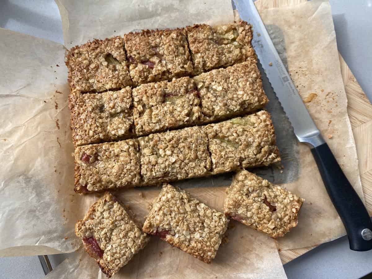 Golden brown rhubarb and ginger flapjacks in a baking tin, sliced into bars.