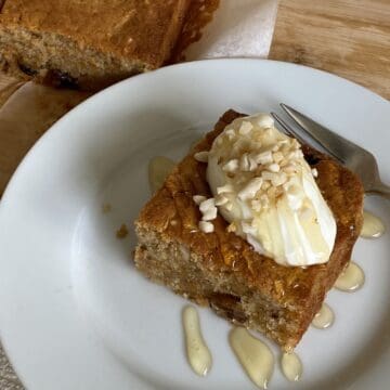 Slice of Carrot Cake Traybake topped with yogurt, honey and nuts.